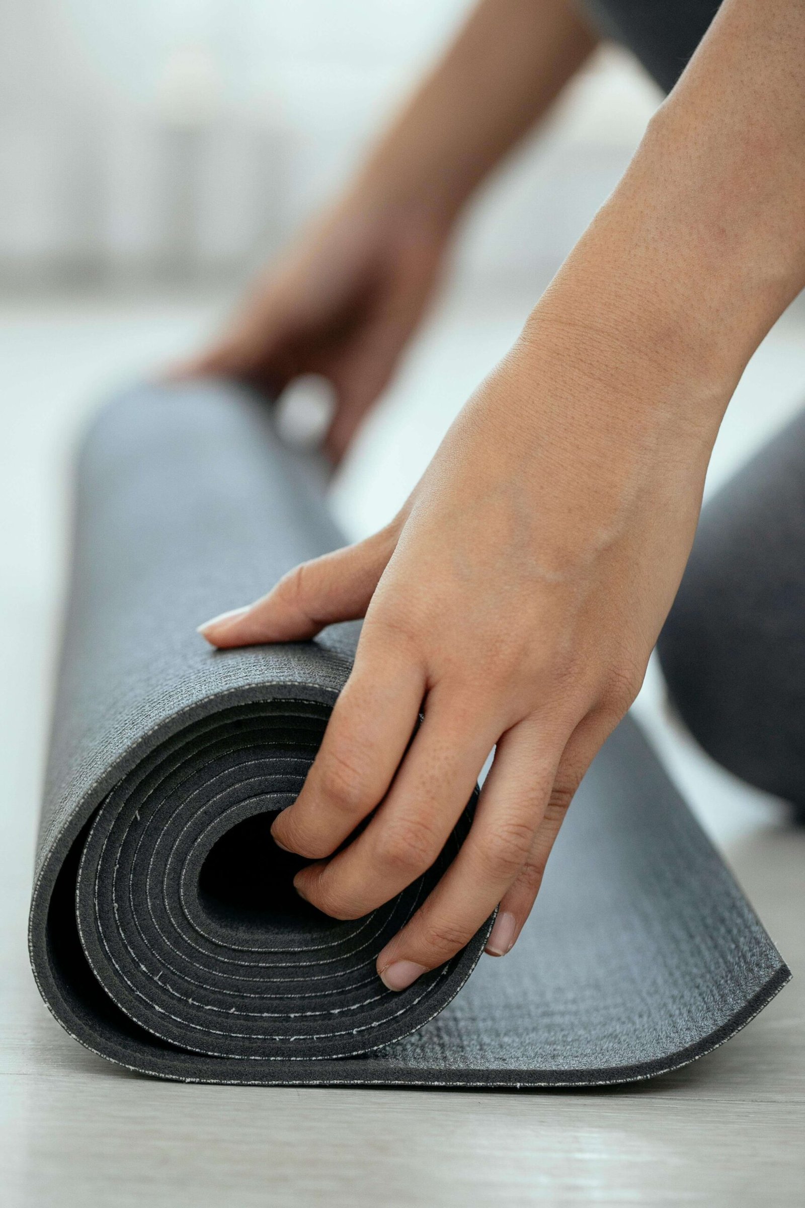 Crop female holding rolled mat on floor. jenniferanistonbody.com