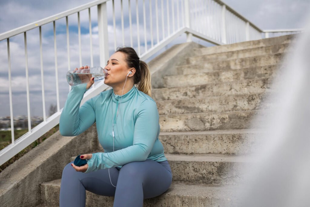 Overweight woman hydrating after exercise. jenniferanistonbody.com