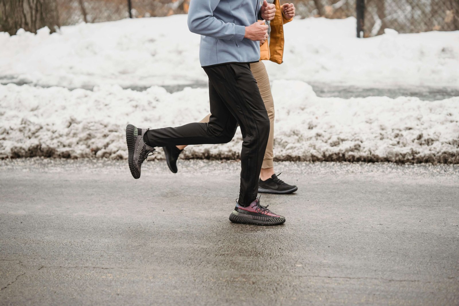 Crop unrecognizable sportspeople jogging on snowy roadway. jenniferanistonbody.com