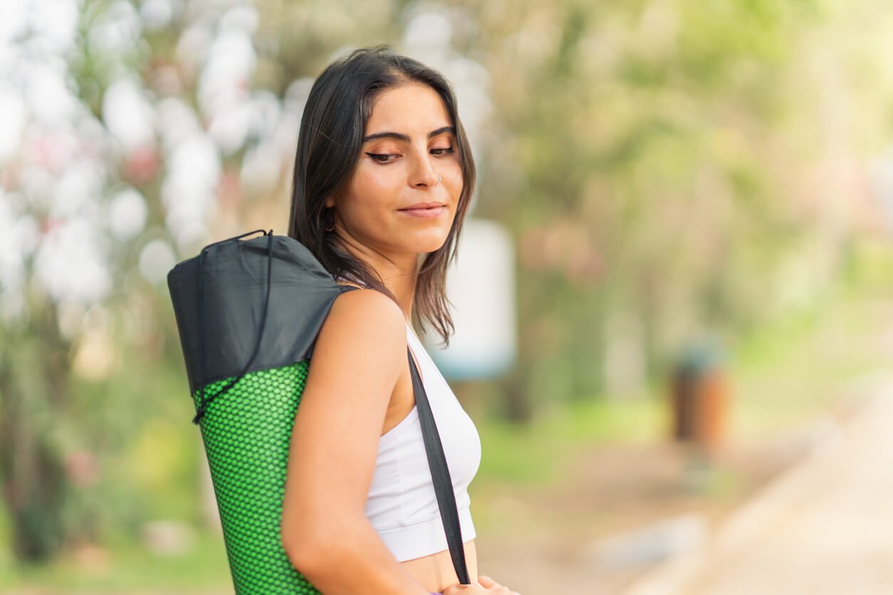 Young sporty woman, posing with her mat over her shoulder. jenniferanistonbody.com