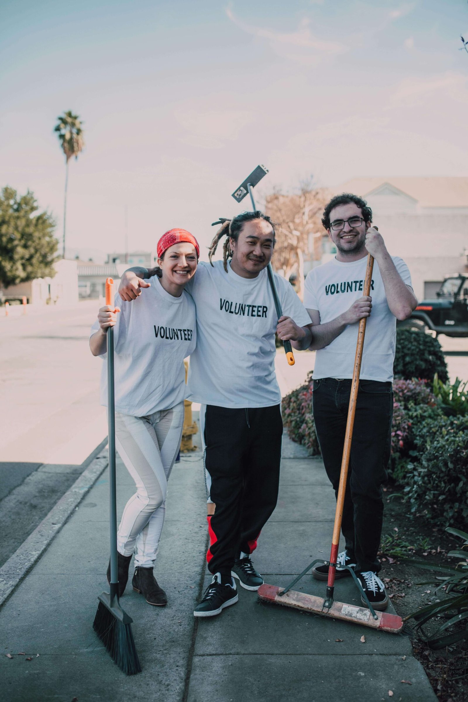 Men and a Woman Standing on the Street while Holding Mops and a Broom. jenniferanistonbody.com