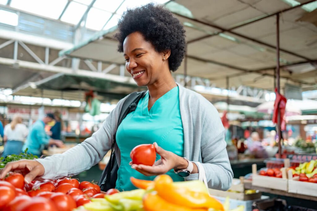 Woman buying tomatoes at the market. jenniferanistonbody.com