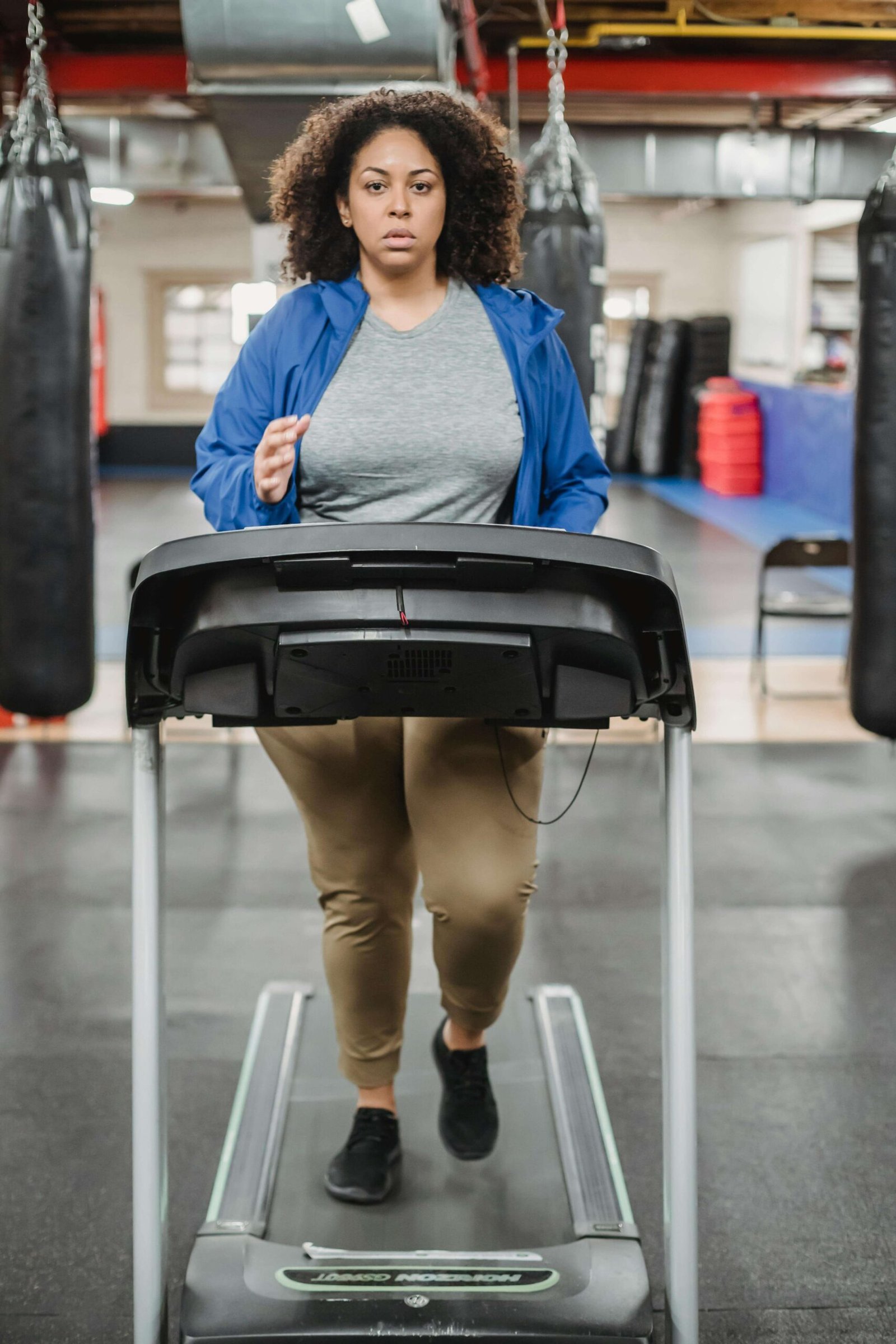 Thoughtful woman training on treadmill in fitness club. jenniferanistonbody.com